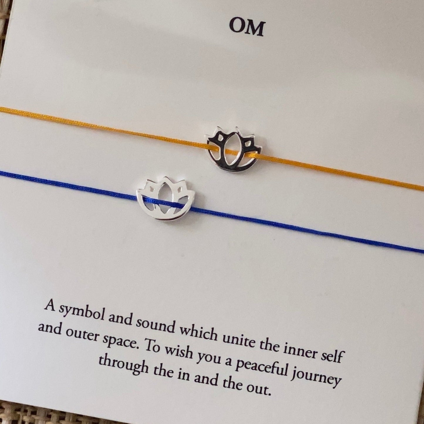 Yellow and blue cord lotus charm bracelets displayed on a meaning card