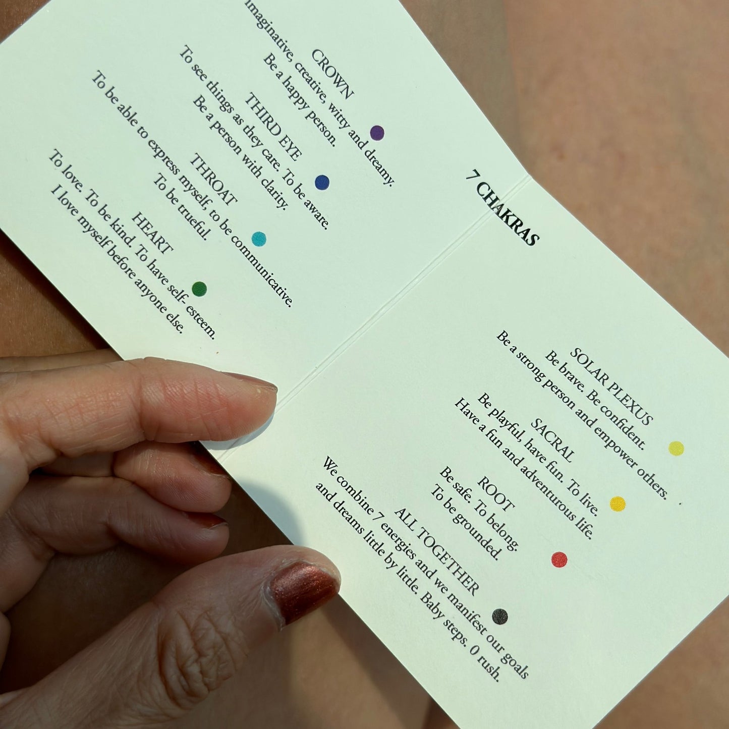 Hand holding a folded seven-chakra meaning card